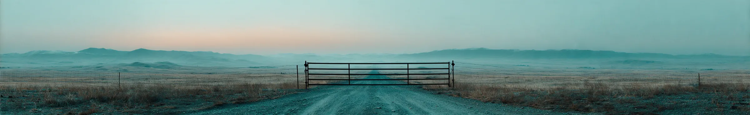 Illustration: a closed ranch gate across a dirt road on open rangeland at dusk